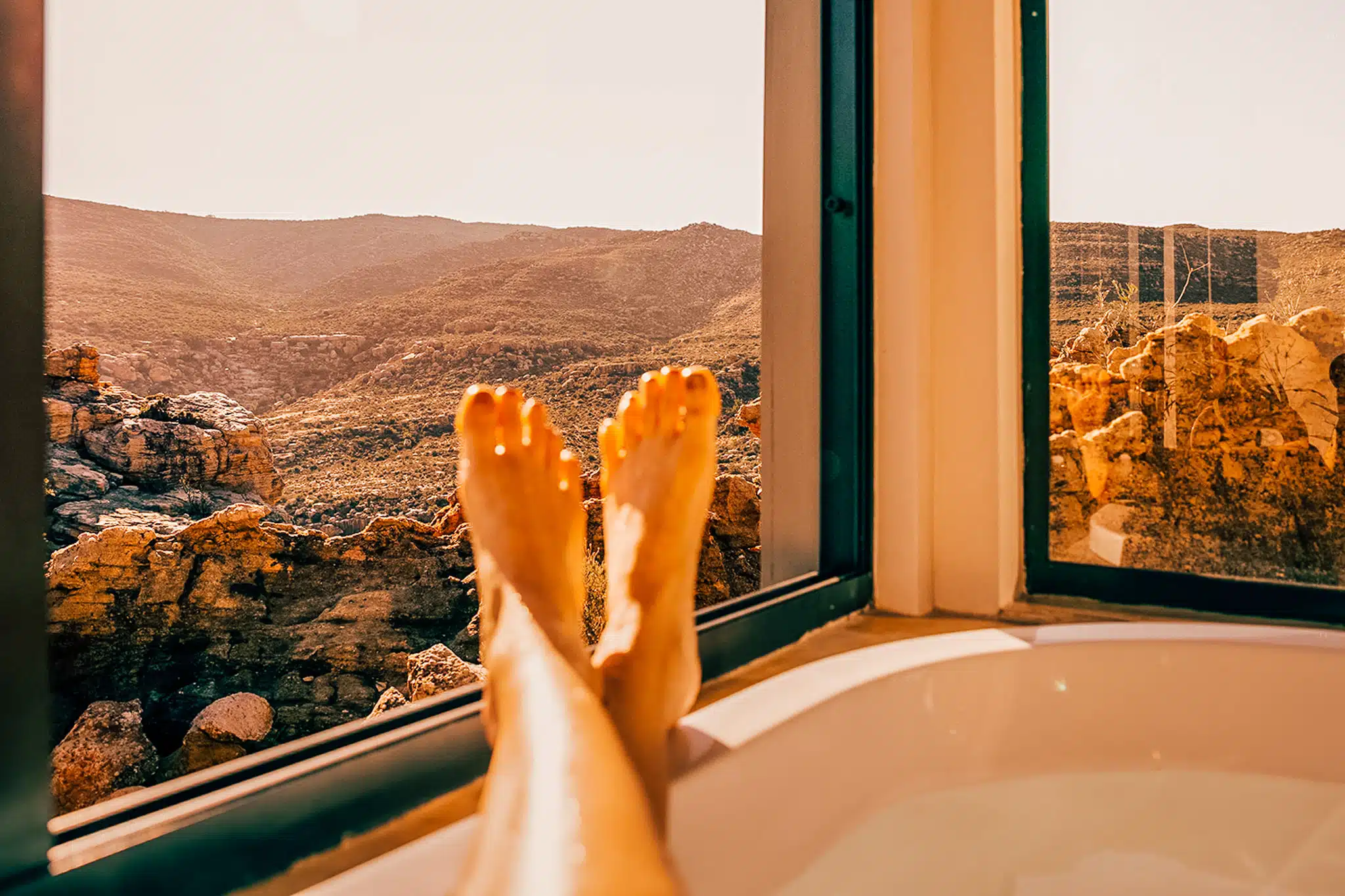 feet resting on the edge of the bathtub overlooking rocks in Cederberg